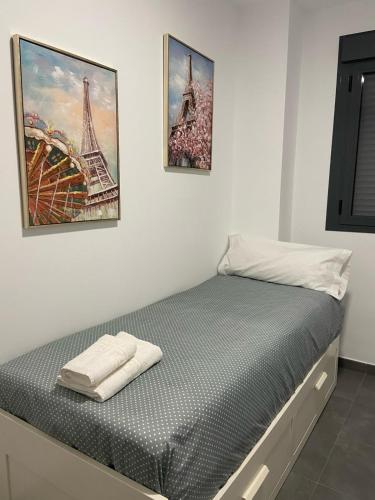 een bed in een kamer met drie foto's aan de muur bij Plaza España Familiar in Sevilla