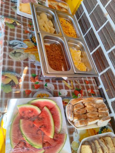 a table topped with trays of food with fruit and bread at Pousada Encantos de Maceió in Maceió