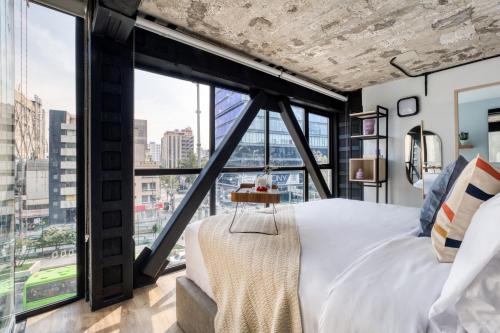 1 dormitorio con 1 cama y ventanas grandes en ULIV Florencia, en Ciudad de México