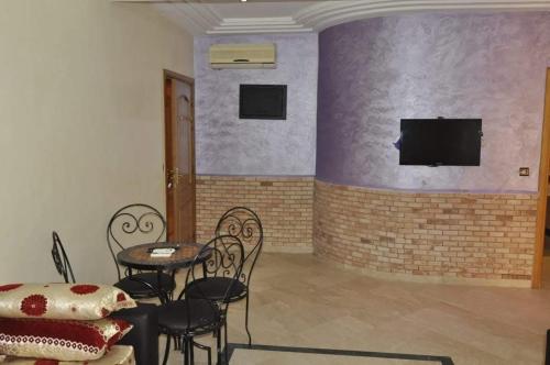 a room with a table and chairs and a tv on a brick wall at Appartement a Marrakech in Marrakech