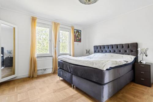 a bedroom with a large bed and two windows at Fräscht och mysigt enkelrum med eget badrum och dusch in Stockholm
