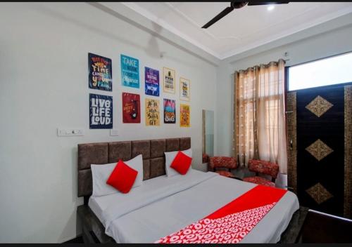 a bedroom with a bed with red pillows and posters on the wall at HOTEL SHREE KANHA in Jaipur