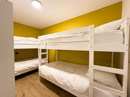 two bunk beds in a room with yellow walls at Mr.Bernard Vakantie Appartementen in De Panne