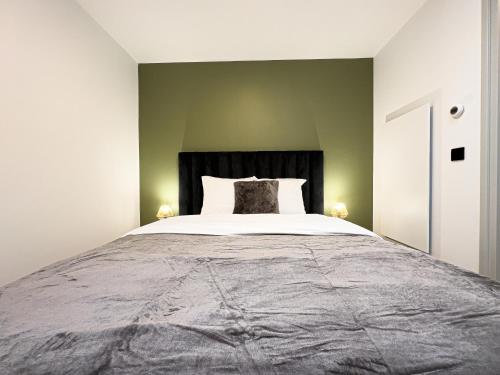 a large bed in a bedroom with green walls at Mr.Bernard Vakantie Appartementen in De Panne