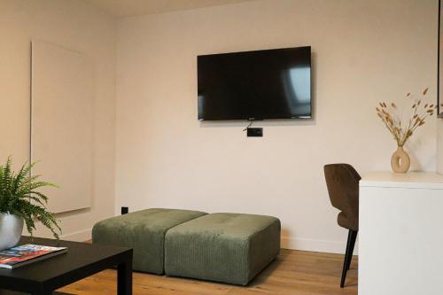 a living room with a bed and a tv on the wall at Mr.Bernard Vakantie Appartementen in De Panne
