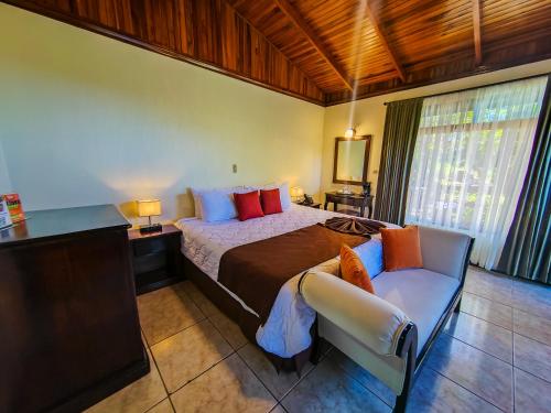een slaapkamer met een groot bed en een stoel bij Hotel & Spa Poco a Poco - Costa Rica in Monteverde Costa Rica
