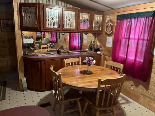 a dining room with a wooden table and pink curtains at Twin Oaks in Bryson City