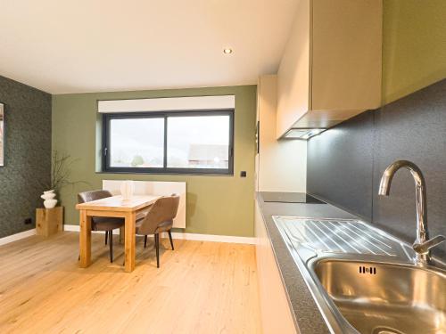 a kitchen with a table and a sink and a window at Mr.Bernard Vakantie Appartementen in De Panne