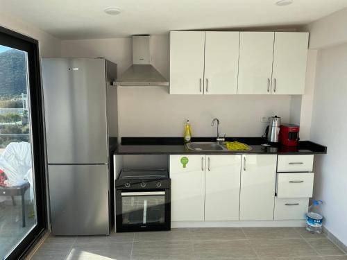 a kitchen with white cabinets and a stainless steel refrigerator at Grand süit 402 in Kalkan