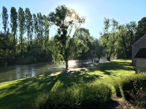 a river with trees and a house in the foreground at Logis Hôtel-Restaurant Domaine de Montecristo in Bourguignons
