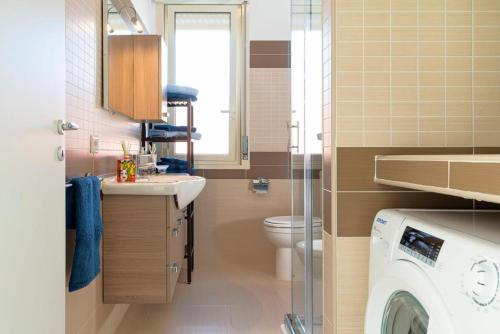a bathroom with a sink and a washing machine at Bombana Beach Apartments in Fontane Bianche