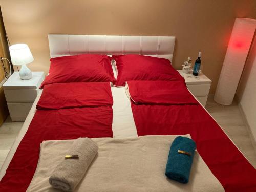 een rood en wit bed met twee handdoeken erop bij Esztergom apartman in Esztergom