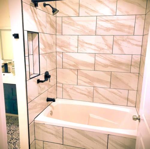 a bathroom with a white tub and a mirror at Beautiful Queen Luxury Suite Near Downtown Norfolk in Norfolk