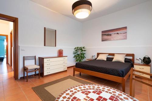 a bedroom with a bed and a dresser and a chair at Bombana Beach Apartments in Fontane Bianche
