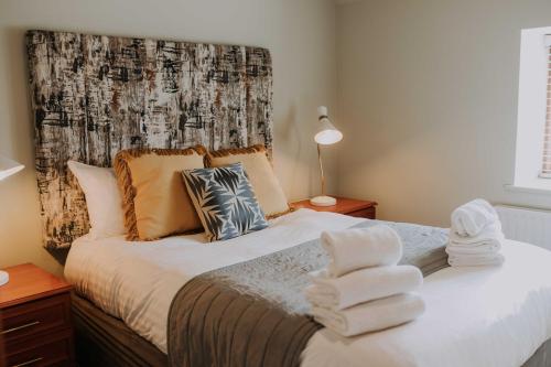 a bedroom with a bed with two towels on it at Pattys Barn Holiday Cottages, Cabins and Venue Hire in Cockerham