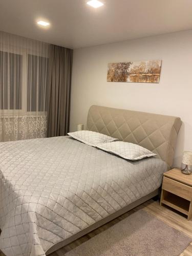 1 dormitorio con 1 cama con edredón blanco en Apartments Victoria, en Panevėžys