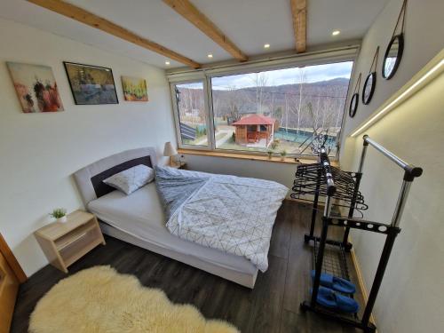 a small bedroom with a bed and a large window at Mountain House Brutusi 17 Bjelasnica Trnovo BIH in Trnovo