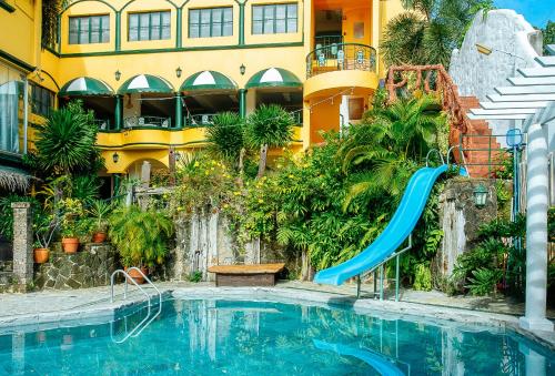 a swimming pool with a slide in front of a building at RedDoorz @ Yahweh Spring Retreat & Resort Laguna in Calamba