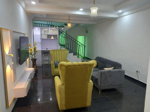 a living room with couches and chairs and a staircase at Mega Pavilion Apartment And Suits Gwarinpa in Gwarinpa