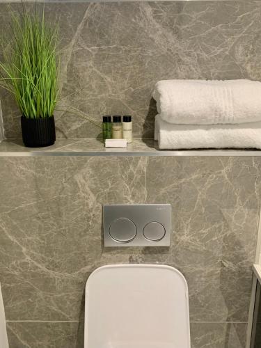a bathroom with a toilet and towels on a wall at OAM The Paramount Rosebank Luxury One-Bedroom in Johannesburg