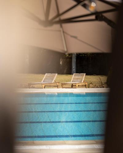 two lounge chairs sitting next to a swimming pool at Hotel rural Finca Vivaldi Nature & Spa in San Miguel de las Dueñas