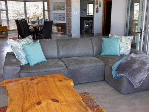 a gray couch with blue pillows and a wooden table at Yzerfontein Beach Accommodation in Yzerfontein