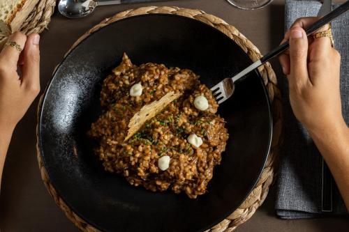 a person holding a fork and a bowl of food at Hotel rural Finca Vivaldi Nature & Spa in San Miguel de las Dueñas