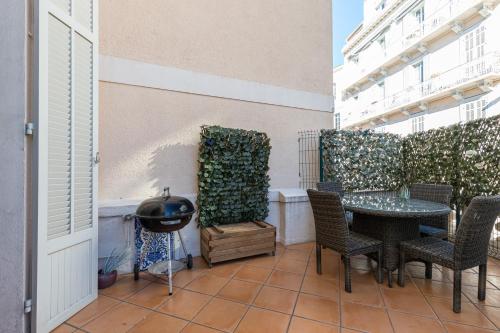 un patio avec une table, des chaises et un barbecue dans l'établissement 77 Avenue de Grasse, à Cannes