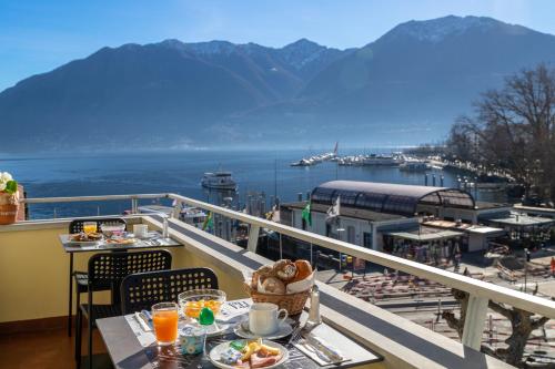 a table with food on a balcony with a view of the water at Hotel Rondinella Locarno in Locarno