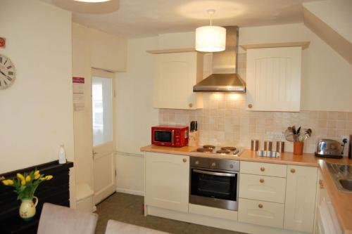 a kitchen with white cabinets and a red microwave at Aelfor Cottage in Barmouth in Barmouth