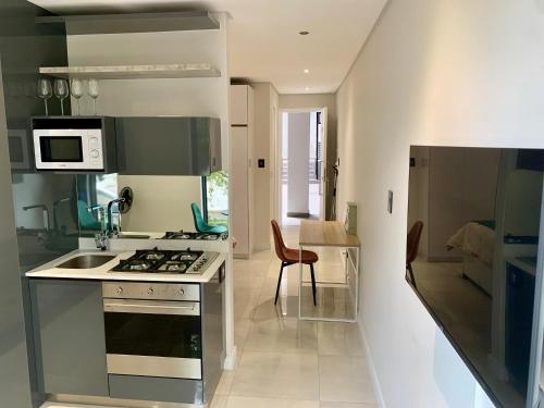 a kitchen with a sink and a stove top oven at OAM The Paramount Rosebank Luxury One-Bedroom in Johannesburg