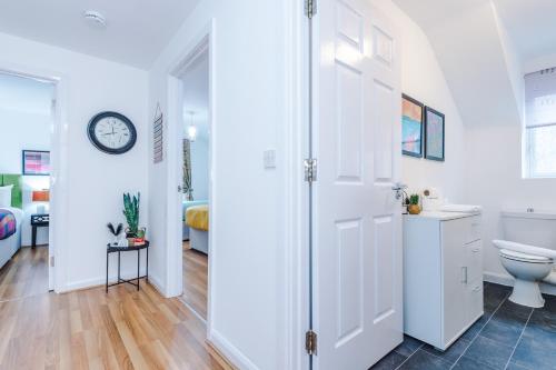 a white bathroom with a toilet and a clock on the wall at Charming 2Bed Retreat in Historic Coventry in Coventry