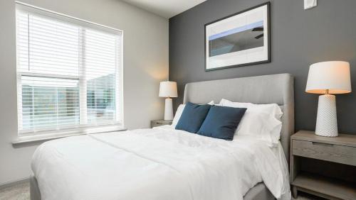 ein Schlafzimmer mit einem weißen Bett mit blauen Kissen und einem Fenster in der Unterkunft Landing Modern Apartment with Amazing Amenities (ID6626X61) in Fishers