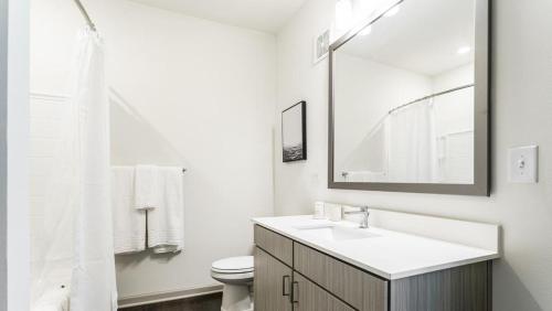 ein weißes Badezimmer mit einem Waschbecken und einem Spiegel in der Unterkunft Landing Modern Apartment with Amazing Amenities (ID6626X61) in Fishers