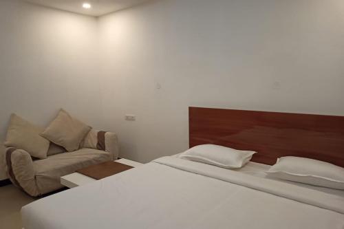 KaglipurにあるAaditya Greensのベッドルーム(ベッド1台、ソファ付)