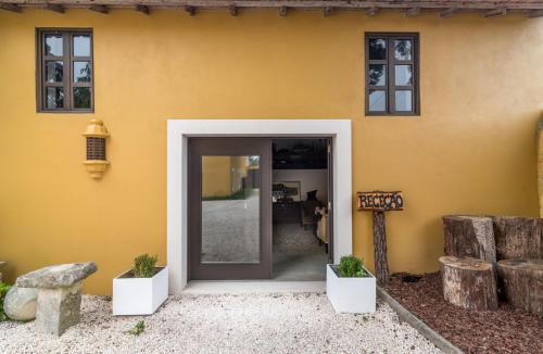an open door of a yellow house with potted plants at Casa De Campo Colmeal in Mira