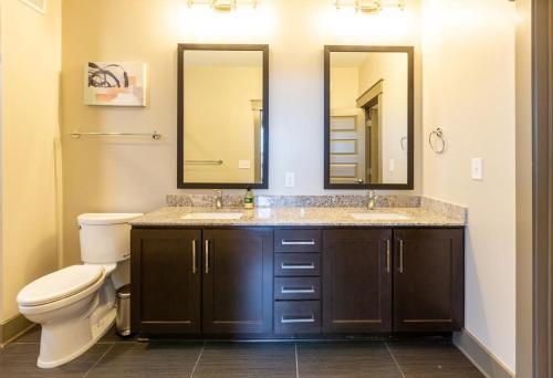 a bathroom with two sinks and a toilet with two mirrors at Landing Modern Apartment with Amazing Amenities (ID917) in Dallas
