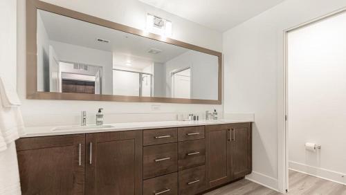La salle de bains est pourvue d'un lavabo et d'un grand miroir. dans l'établissement Landing Modern Apartment with Amazing Amenities (ID7569X30), à Fort Myers