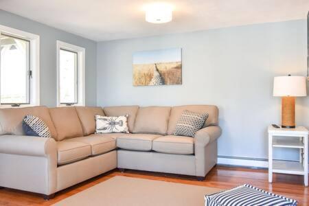 a living room with a brown couch and two windows at 400 Yards to the Beach Dogs Welcome in Dennis