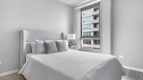 a white bedroom with a large bed and a window at Landing Modern Apartment with Amazing Amenities (ID4859X97) in Chicago