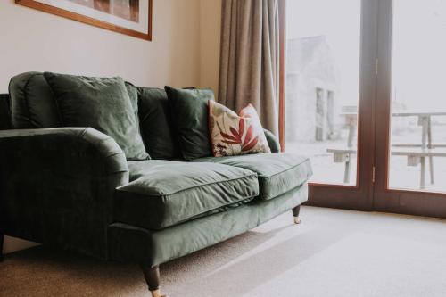 a green couch in a living room with a window at Pattys Barn Holiday Cottages, Cabins and Venue Hire in Cockerham