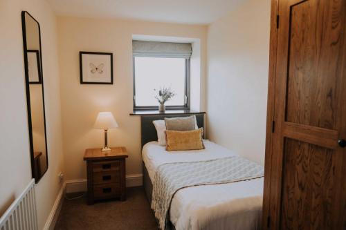 a small bedroom with a bed and a window at Pattys Barn Holiday Cottages, Cabins and Venue Hire in Cockerham