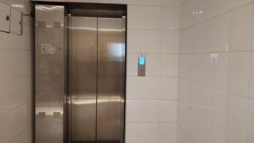 a metal elevator in a bathroom with white tiles at Goroomgo New Paradise Industrial Estate Bhubaneswar in Bhubaneshwar