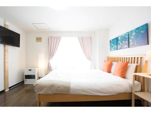 1 dormitorio con 1 cama con almohadas de color naranja y ventana en Haimu Shanzerize 7,12 - Vacation STAY 11290, en Sapporo