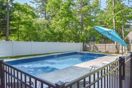 a swimming pool with a blue umbrella on a fence at Contemporary Gem with Private Pool in Barnstable