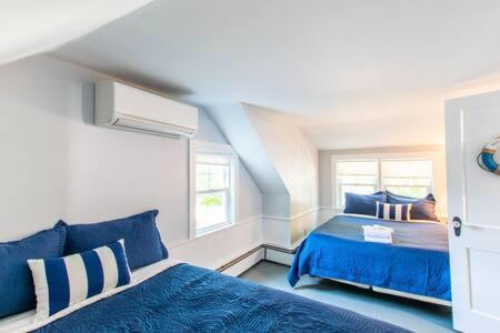 a blue bedroom with two beds and a window at 3 Min Walk to Beach Large Fenced Yard in Yarmouth