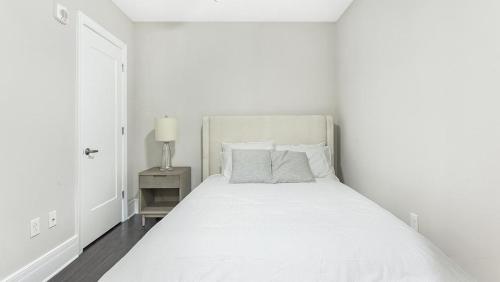 a white bedroom with a large bed with white sheets and pillows at Landing Modern Apartment with Amazing Amenities (ID1239X428) in Richmond