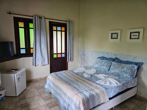 a bedroom with a bed and a tv and two windows at Canto Verde Pousada in Lençóis