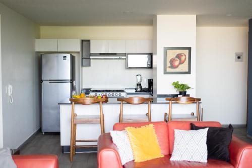 a living room with a red couch and a kitchen at Departamento 2 habitaciones en la Americana in Guadalajara