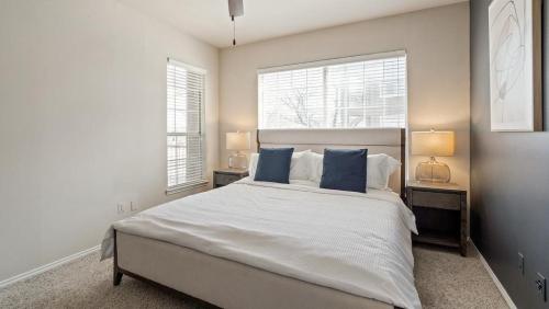 1 dormitorio con 1 cama blanca grande con almohadas azules en Landing Modern Apartment with Amazing Amenities (ID8229X54), en Plano
